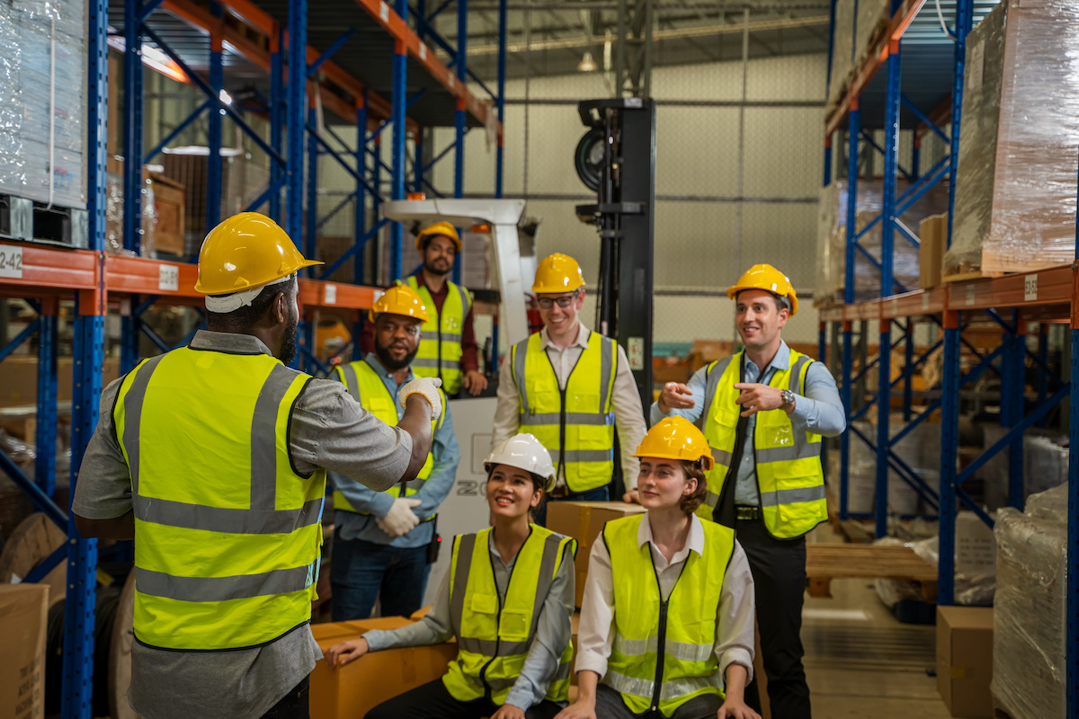 Warehouse workers are meeting together,Group of multicultural logistics employees working as a team in in a large distribution warehouse.